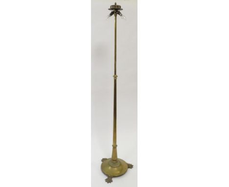 A 20th century brass adjustable standard lamp, raised lion paw feet