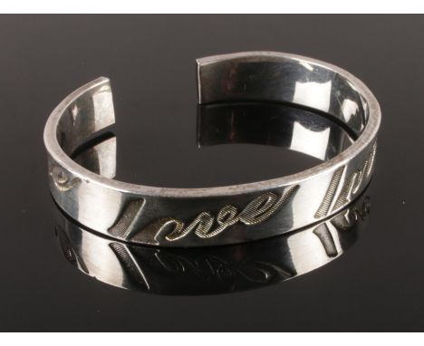 A silver bangle, embossed with 'Love'. Stamped 925. Total weight: 26.50g.  