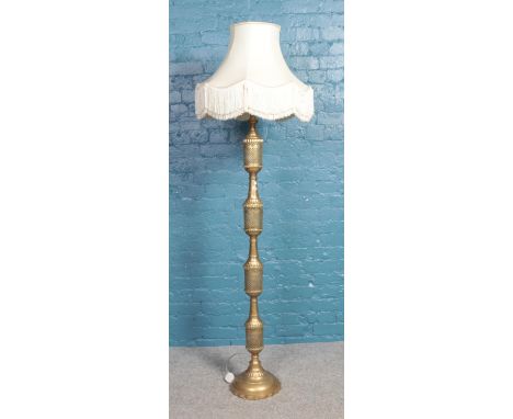 A large brass standard lamp with pierced decoration, together with frilled cream shade. Total height: 192cm.  