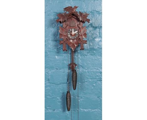 A black forest style cuckoo clock, with foliate decoration and bird to the top.  