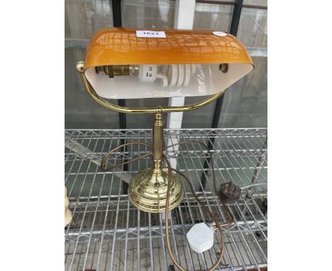 A DECORATIVE BRASS BANKERS LAMP WITH ORANGE GLASS SHADE