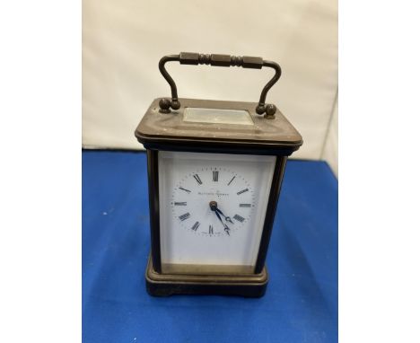 A MATTHEW NORMAN BRASS CARRIAGE CLOCK WIT WHITE ENAMEL FACE, ROMAM NUMERALS AND VISUAL ESCAPEMENT