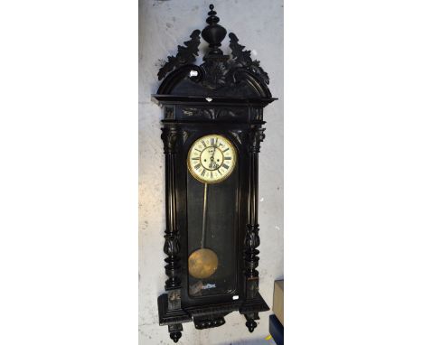 A 19th century Vienna wall clock in an ebonised case with urn, flora and acanthus leaf decoration above enamel dial set with 