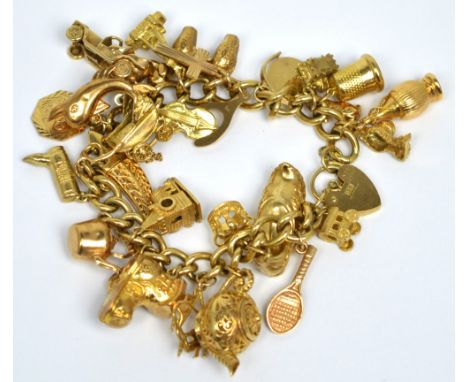 A 9ct yellow gold curb link charm bracelet with twenty-seven 9ct gold and yellow metal charms to include a yellow metal churc