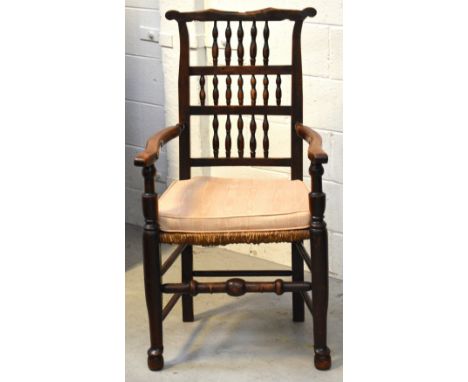 A 19th century elm carver with turned ladder back, abstract arms, rush seat on turned supports to pad feet and turned cross-s