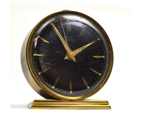 A vintage Cyma brass alarm clock, black dial set with baton numerals, diameter 5.5cm.