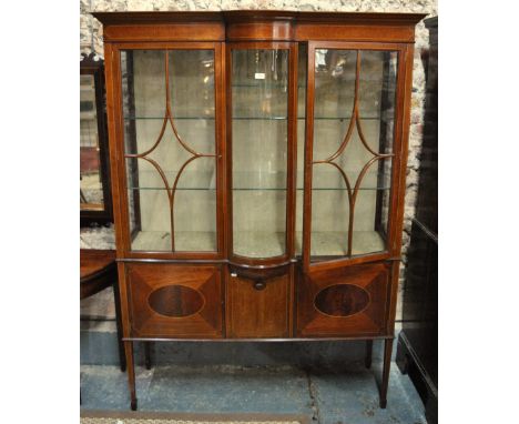 An Edwardian Sheraton revival astragal glazed satinwood display cabinet, the bowfront glazed centre panel flanked by doors en