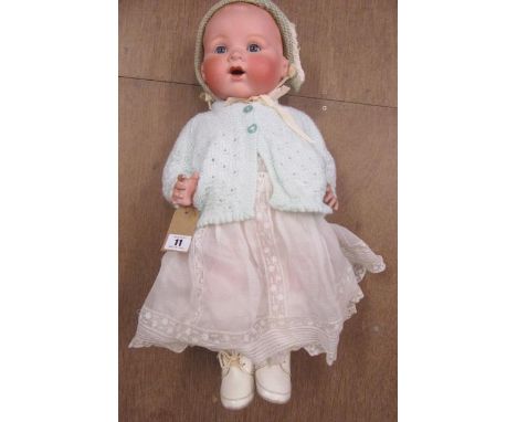 An Armand Marseille bisque socket head baby doll with fixed blue glass eyes and open mouth, moulded hair, bent limbed composi