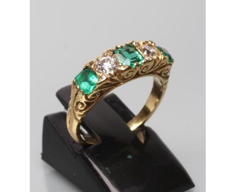 A FIVE STONE EMERALD AND DIAMOND HALF HOOP RING, the three square cut emeralds claw set with two round brilliant cut diamonds