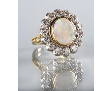 AN OPAL AND DIAMOND CLUSTER DRESS RING, the oval polished cabochon opal collet set to a border of fourteen brilliant cut claw