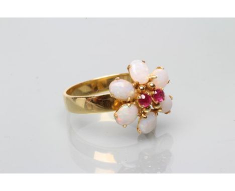 A RUBY AND OPAL CLUSTER FLOWER RING, the two small circular facet cut rubies point set within a border of six oval polished c