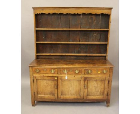 A GEORGIAN OAK DRESSER, c.1800, the boarded delft rack with moulded cornice over waved frieze and three shelves, the base wit