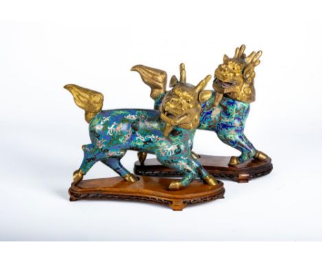 A PAIR OF CHINESE CLOISONNE ENAMEL KYLIN, with cast and engraved gilt metal heads, tails and hooves, the bodies with pink, wh