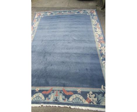 A CHINESE WASHED AND FRINGED CARPET, late 20th century, in powder blue with a wide border of stylised flowers and foliage in 