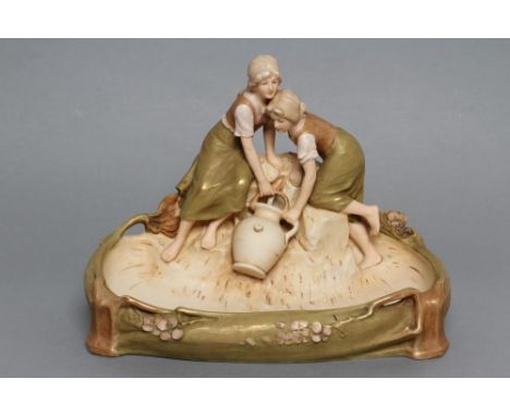 A ROYAL DUX PORCELAIN FIGURAL SIDE DISH/FLOWER HOLDER, early 20th century, modelled as two young girls drawing water, seated 