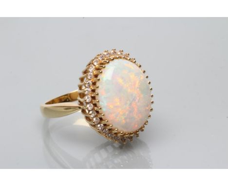 AN OPAL AND DIAMOND CLUSTER DRESS RING, the oval cabochon polished opal claw set to a border of small round brilliant cut dia