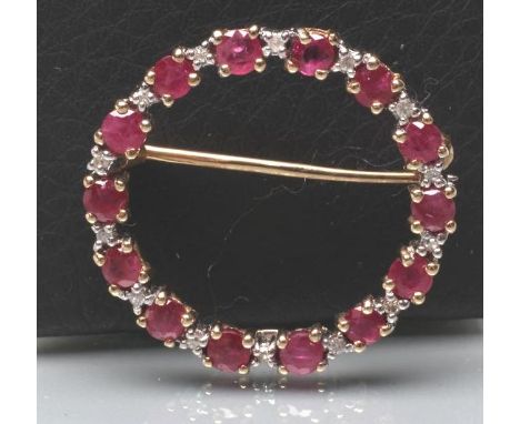 A RUBY AND DIAMOND CIRCLET BROOCH, point set with fourteen small facet cut rubies with diamond points between, stamped 9k (Es