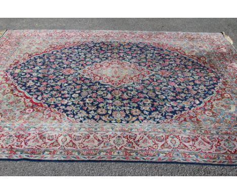 A PERSIAN CARPET, the puce field with repeating flower pattern in shades of blue, green and ivory and centred by a similar gu