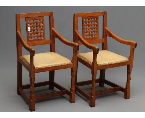 A PAIR OF PETER HEAP ADZED OAK ELBOW CHAIRS, the straight top rail on pierced latticed panel back, downswept arms on shaped s