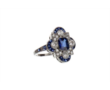 SAPPHIRE AND DIAMOND RING, the step cut sapphire surrounded by round brilliant cut diamonds and calibre cut sapphires, on sap