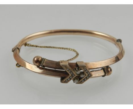 A Victorian gilt metal and seed pearl bangle, having pearl-set double arrow decoration. 