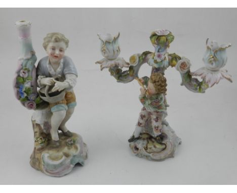 An early 20th century Meissen style twin branch candlestick, the base with a figure playing a flute, together with another fi