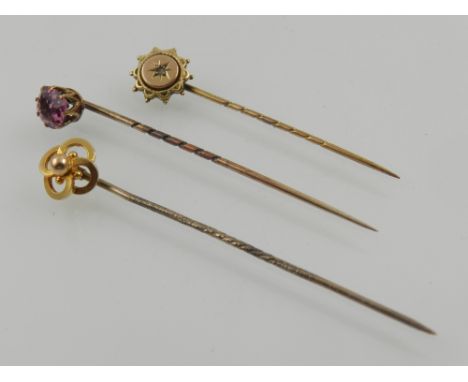 A yellow metal and pink tourmaline stick pin, stamped 9ct, together with two further 9 carat yellow gold stick pins. (3)