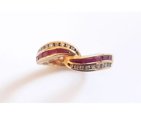 An 18ct yellow gold crossover ring set with baguette cut diamonds and rubies, (L.5).