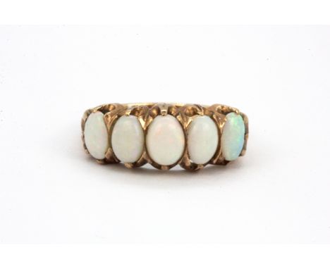 A yellow metal (tested high carat gold) ring set with five oval cut cabochon cut opals, (P).