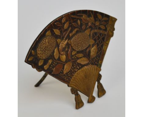 A Japanese bronzed metal menu holder in the form of a fan decorated in relief with birds and blossoms, and with two tassels, 