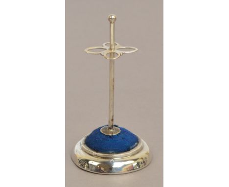 An Edward VII hallmarked silver hat pin stand of plain form with four shaped pin supports, a circular pin cushion and a stepp
