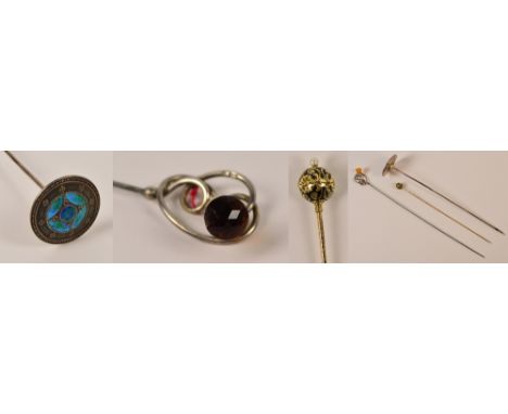 A Liberty style hatpin with enamel decorated circular finial, unmarked, a loop design amber glass thistle decorated example a