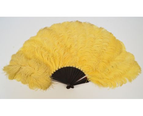 An Edwardian folding feather fan, the simulated tortoiseshell guards and sticks of plain form, and the leaf formed by yellow 