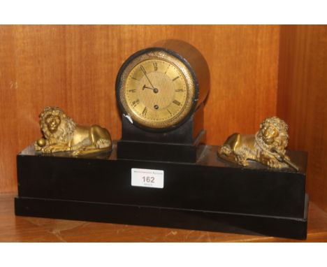 A BLACK SLATE MANTEL CLOCK WITH A PAIR OF BRASS LIONS A/F