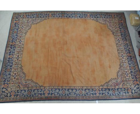 A LARGE RUST GROUND MIDDLE EASTERN CARPET with cream spandrels and blue geometric borders, 464cm long x 349cm wide Condition 