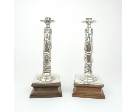 A PAIR OF CHINESE SILVER CANDLESTICK LAMPS cast with sinuous dragons, beneath acanthus leaf and above a monogram on a square 