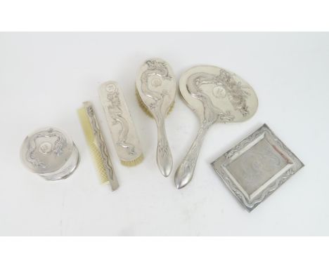 A CHINESE SILVER BRUSH SET cast with dragons, surrounding R monogram, on a textured ground, comprising;pin tray, 16 x 12cm, i