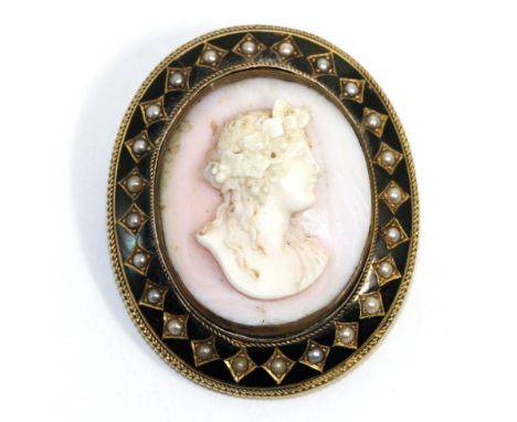 A carved conch shell cameo brooch/pendant, depicting the bust of a Bacchante, within a black enamel frame set with seed pearl