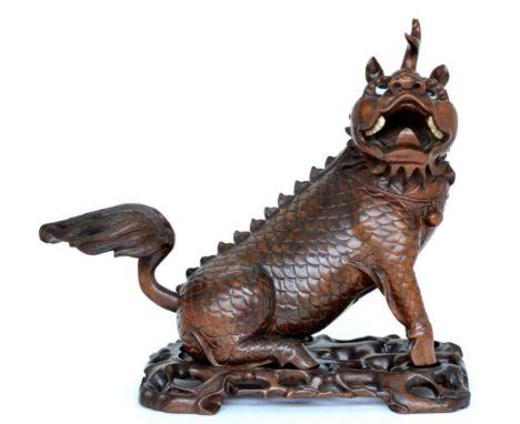 A Chinese carved hardwood figure of a Kylin, late 19th century, seated on a separate scroll carved and pierced stand, 41cm lo