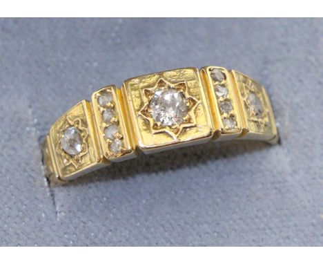 A diamond band ring, three graduated old cut diamonds in star settings to square frames, spaced by diamond accents, total est