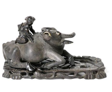 A Chinese carved wood figure of an ox and rider, early 20th century, recumbent with bone eyes and teeth, 28cm long, on a wood