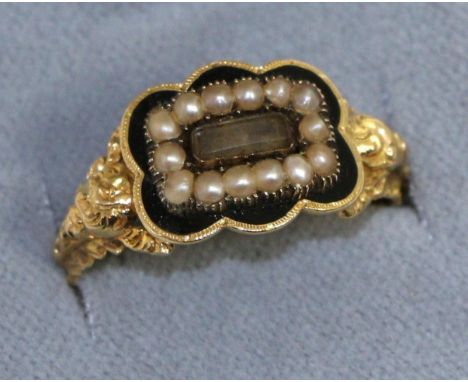 A George IV 18 carat gold enamel and seed pearl mourning ring, a central glazed plaque within a border of seed pearls and a b