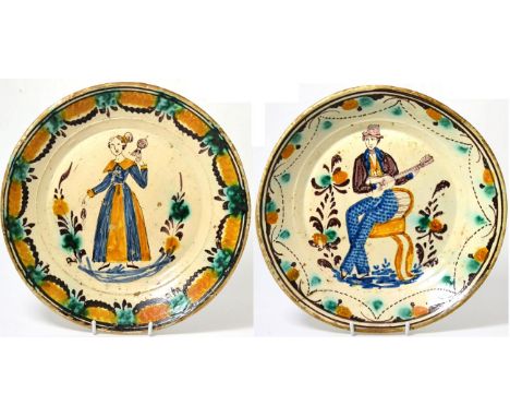 A central European faience circular dish, early 19th century, painted in colours with a seated gentleman playing a guitar, 30