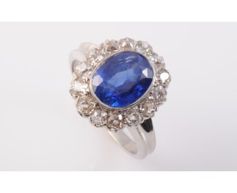 A SAPPHIRE AND DIAMOND RING, the oval mixed cut sapphire collet set within a scalloped edge surround set with fourteen old br