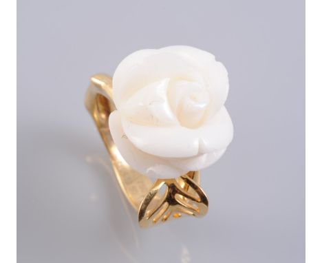 A CORAL AND DIAMOND RING BY CHRISTIAN DIOR, the large carved coral flower head set raised to the centre of a moulded band to 