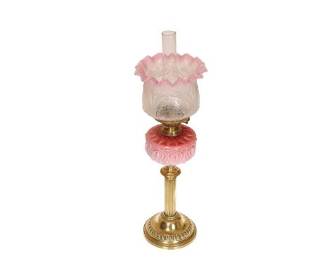 A VICTORIAN BRASS AND CASED GLASS OIL LAMP, the columnar stem supporting a reservoir moulded in Art Nouveau style.  Overall 7