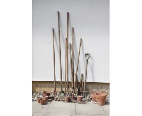 A quantity of vintage garden tools, including rakes, a scythe, hoes, etc, together with a quantity of terracotta flower pots