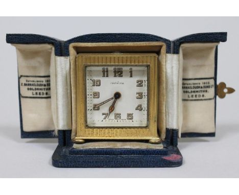 A brased cased Zenith travel alarm clock of swuare form with original blue leather box, gross height 7.5cm.  