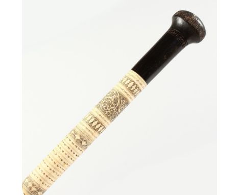 A GOOD INDIAN BONE WALKING STICK, etched with calligraphy, insects and emblems, with wooden knop handle. 3ft long.