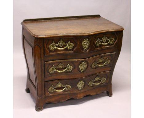 A LOUIS XV STYLE FRENCH OAK SERPENTINE FRONT COMMODE, comprising two short and two long drawers, all with ornate cast brass h